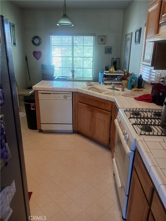 kitchen with tile counters, white appliances, and decorative light fixtures