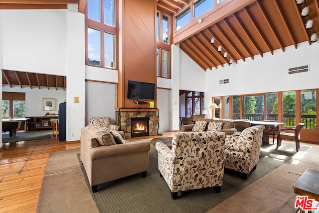 living room featuring beam ceiling, hardwood / wood-style floors, and high vaulted ceiling