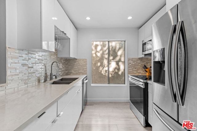 kitchen featuring decorative backsplash, sink, stainless steel appliances, and white cabinets