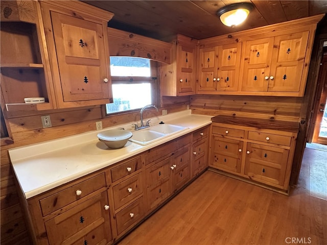 kitchen with light wood-type flooring, wood walls, sink, and wood ceiling