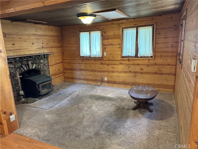 unfurnished room featuring wooden walls, wood ceiling, hardwood / wood-style floors, and a wood stove