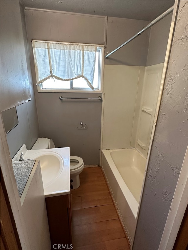 full bathroom with wood-type flooring, vanity, shower / bath combination, and toilet