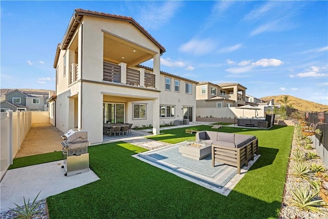 rear view of property with a lawn, a patio, and an outdoor living space with a fire pit