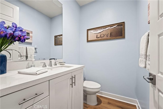 bathroom with hardwood / wood-style flooring, toilet, and vanity