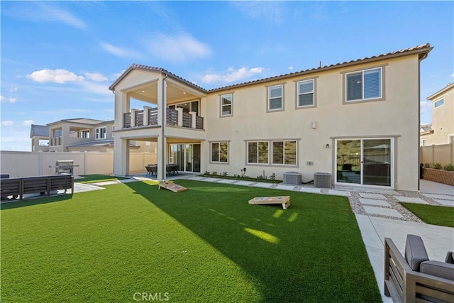 back of house featuring a balcony, central AC, a yard, and a patio