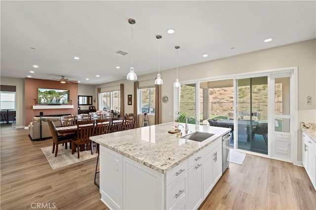 kitchen with dishwasher, white cabinetry, a kitchen island with sink, sink, and pendant lighting