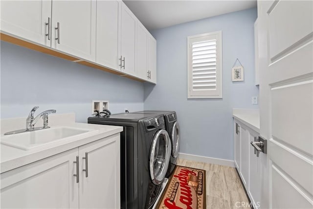 laundry area with sink, light wood-type flooring, cabinets, and washer and dryer