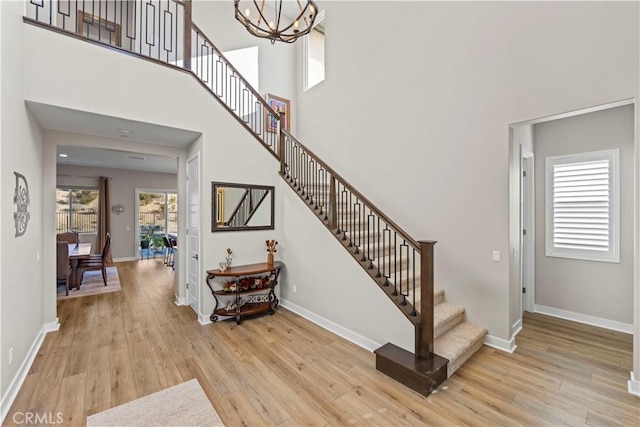 stairs with wood-type flooring, plenty of natural light, and a towering ceiling