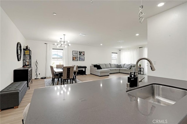 kitchen with a wealth of natural light, sink, light hardwood / wood-style floors, and a notable chandelier