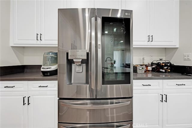 kitchen with stainless steel fridge with ice dispenser and white cabinetry