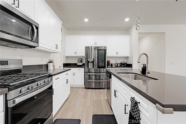 kitchen featuring white cabinetry, sink, stainless steel appliances, decorative light fixtures, and light wood-type flooring