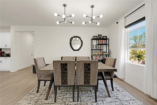 dining room with light wood-type flooring and an inviting chandelier