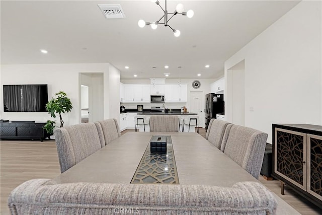 dining area with a chandelier and light hardwood / wood-style flooring