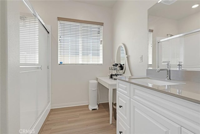 bathroom with hardwood / wood-style floors, vanity, and a shower with shower door