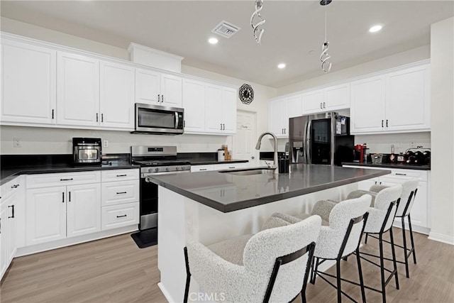 kitchen featuring an island with sink, sink, appliances with stainless steel finishes, and light hardwood / wood-style flooring