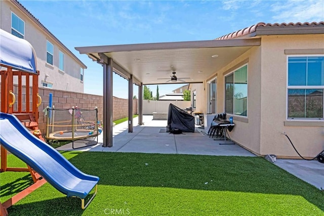 exterior space featuring a yard, a trampoline, a patio, and ceiling fan