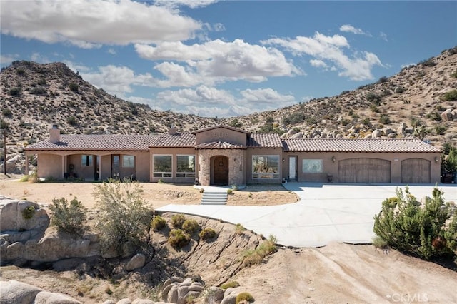 view of front of house with a mountain view, a garage, a tiled roof, a chimney, and concrete driveway