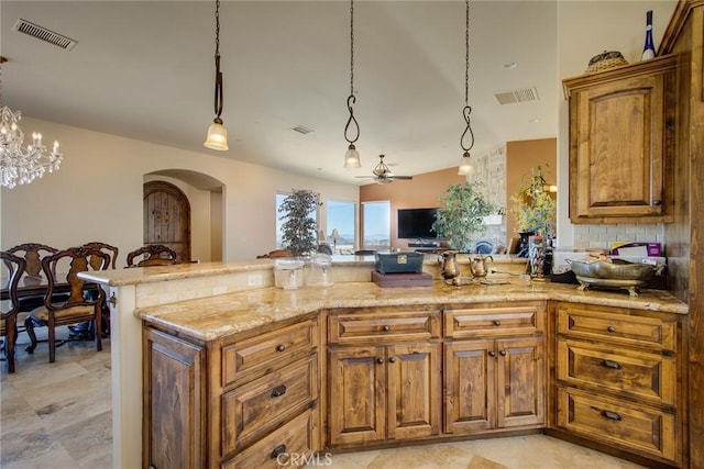 kitchen featuring light stone counters, visible vents, brown cabinets, and arched walkways