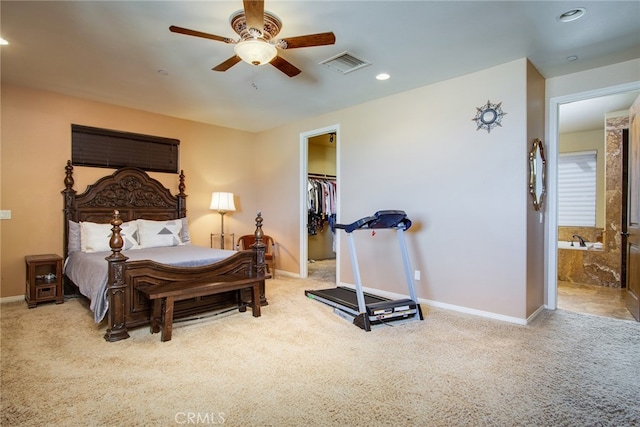 bedroom with ensuite bath, ceiling fan, a walk in closet, and light colored carpet