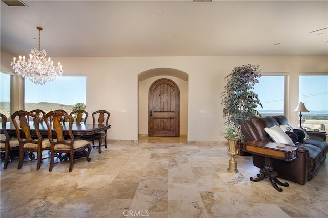 dining space featuring a chandelier, a wealth of natural light, arched walkways, and visible vents