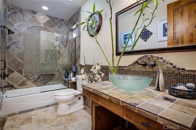 full bathroom featuring shower / bath combination with glass door, vanity, tile walls, and toilet