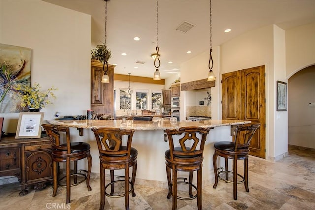 kitchen with recessed lighting, light stone counters, visible vents, a peninsula, and arched walkways