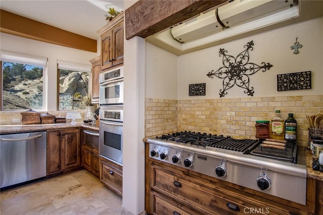 kitchen featuring a warming drawer, light stone countertops, appliances with stainless steel finishes, and decorative backsplash