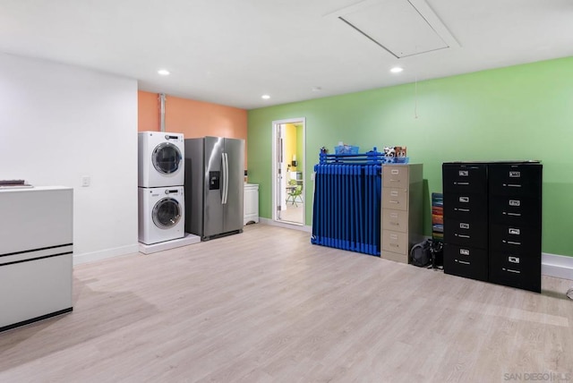 laundry room featuring light wood-type flooring and stacked washer and dryer