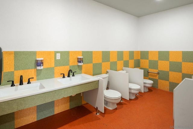 bathroom featuring toilet and double sink