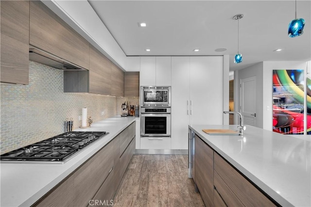 kitchen featuring modern cabinets, appliances with stainless steel finishes, light countertops, and a sink