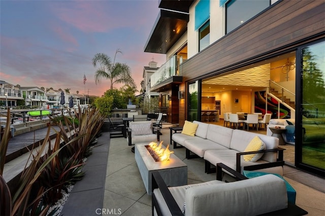 patio terrace at dusk featuring an outdoor living space with a fire pit