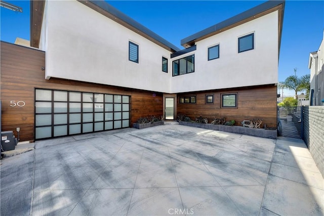 back of house with fence, stucco siding, and an attached garage