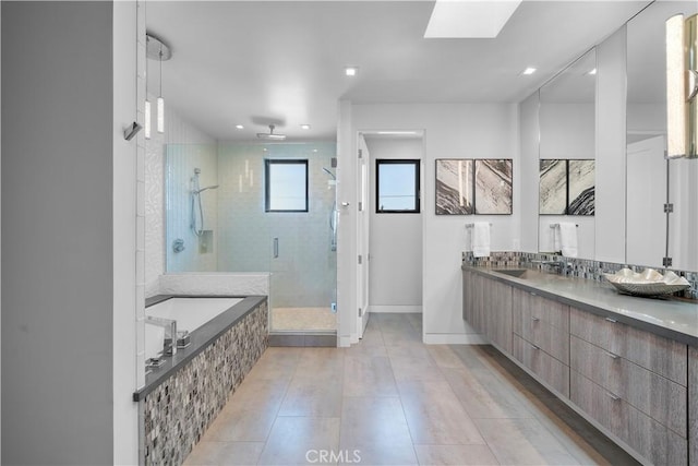 full bathroom featuring a stall shower, tile patterned floors, a garden tub, vanity, and a skylight