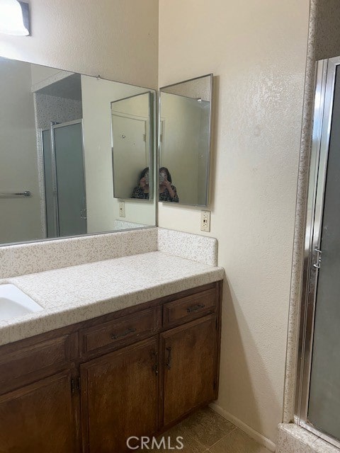 bathroom with walk in shower, vanity, and tile patterned floors