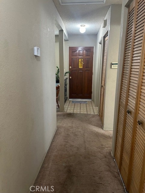 hall with light colored carpet and a textured ceiling