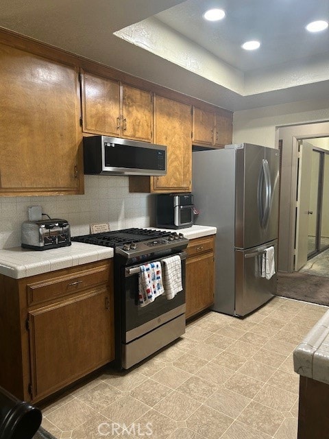 kitchen with tile counters, stainless steel appliances, and tasteful backsplash