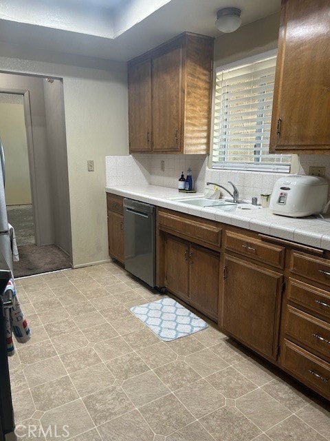 kitchen featuring dark brown cabinets, dishwasher, sink, and tasteful backsplash