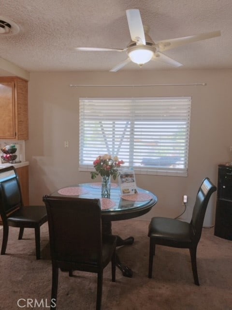 carpeted dining room featuring a textured ceiling and ceiling fan