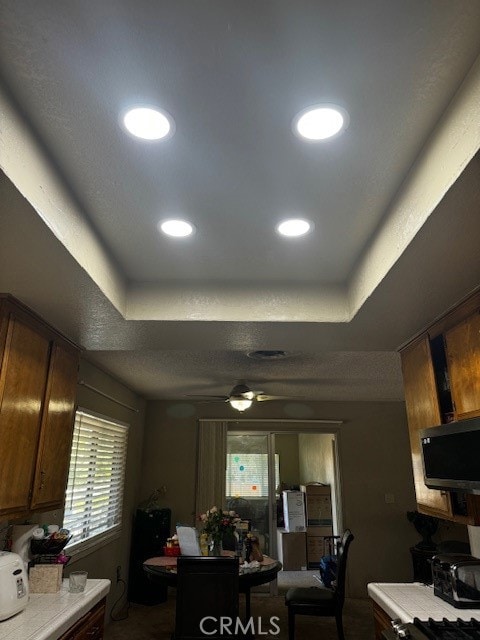 kitchen with ceiling fan and a raised ceiling