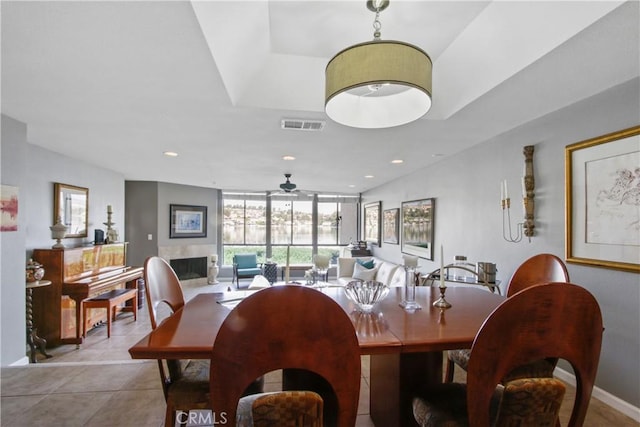 dining room with ceiling fan, a fireplace, and light tile patterned floors