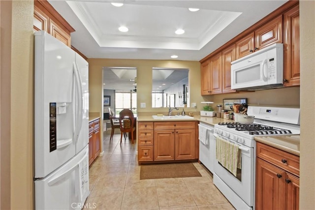 kitchen with white appliances, sink, light tile patterned floors, a tray ceiling, and kitchen peninsula