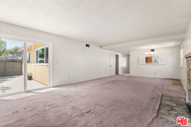 unfurnished living room with light carpet, a chandelier, and a textured ceiling