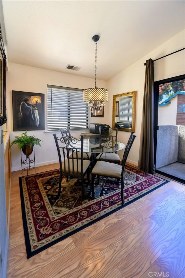 dining space with light hardwood / wood-style flooring, a chandelier, and lofted ceiling