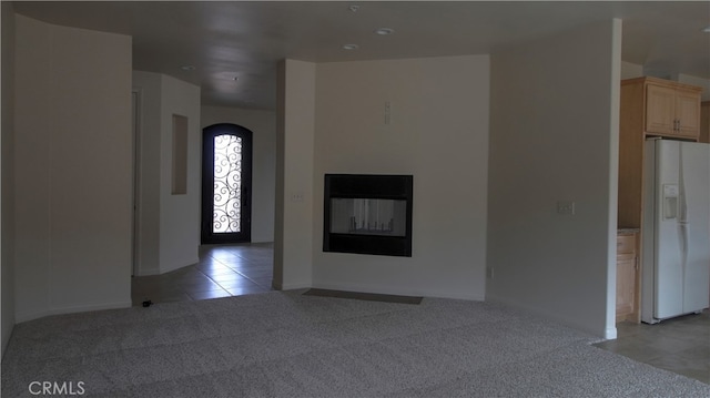 unfurnished living room featuring light carpet and a multi sided fireplace