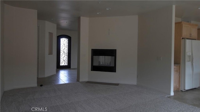 56925 Hidden Gold Ct, Yucca Valley, CA 92284 - unfurnished living room featuring light carpet, a glass covered fireplace, arched walkways, and light tile patterned floors