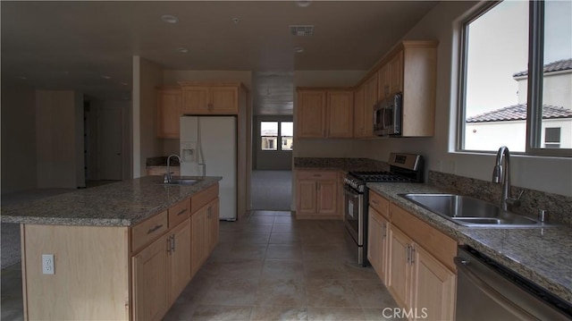 56925 Hidden Gold Ct, Yucca Valley, CA 92284 - kitchen with appliances with stainless steel finishes, light brown cabinets, a kitchen island with sink, light stone countertops, and light tile patterned floors