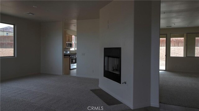 56925 Hidden Gold Ct, Yucca Valley, CA 92284 - unfurnished living room with carpet flooring, plenty of natural light, and a glass covered fireplace