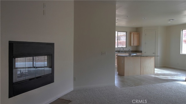 kitchen featuring a center island, light brown cabinets, light carpet, and sink