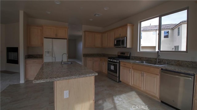 56925 Hidden Gold Ct, Yucca Valley, CA 92284 - kitchen featuring appliances with stainless steel finishes, light brown cabinetry, light stone counters, and an island with sink