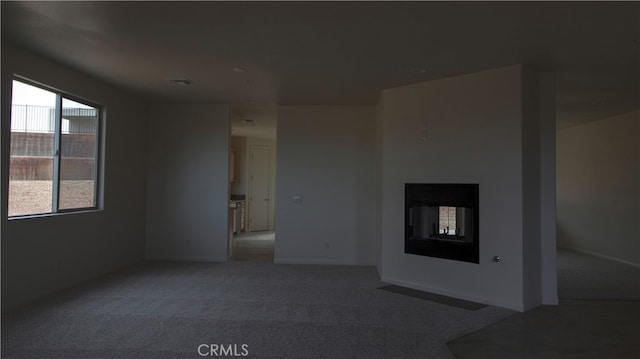 spare room with light colored carpet and a multi sided fireplace